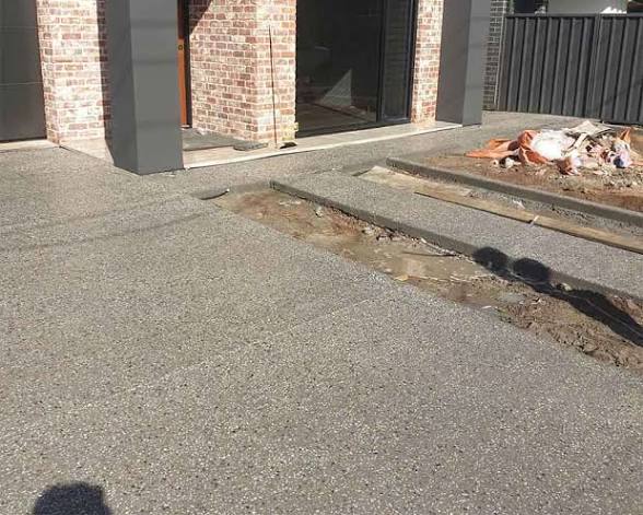 Exposed aggregate driveway poured up to the front entry of a brick home